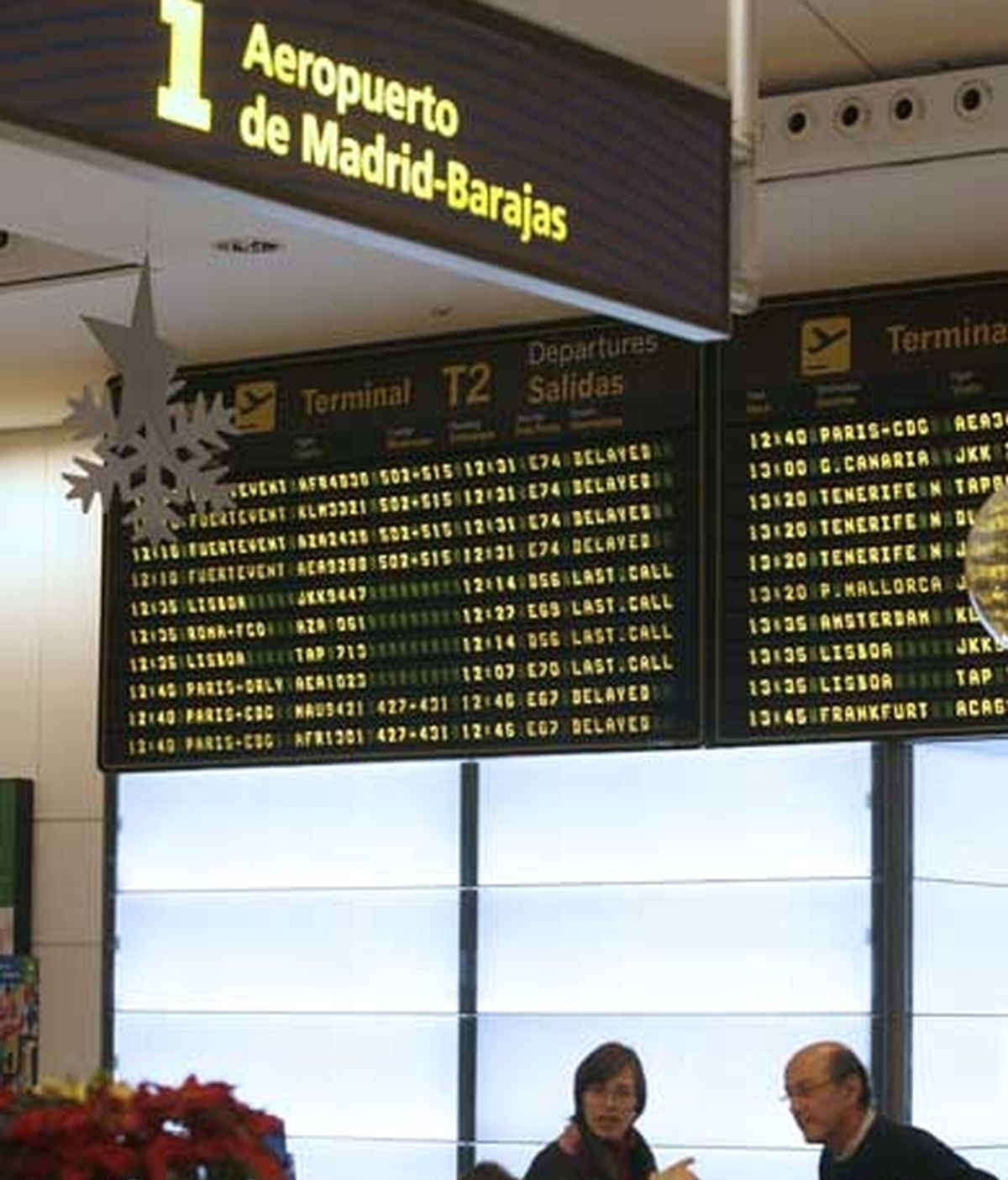 Viajeros reciben información en el aeropuerto de Barajas, bajo los paneles anunciadores que avisan de los retrasos que se prevén para distintos vuelos. Foto: EFE