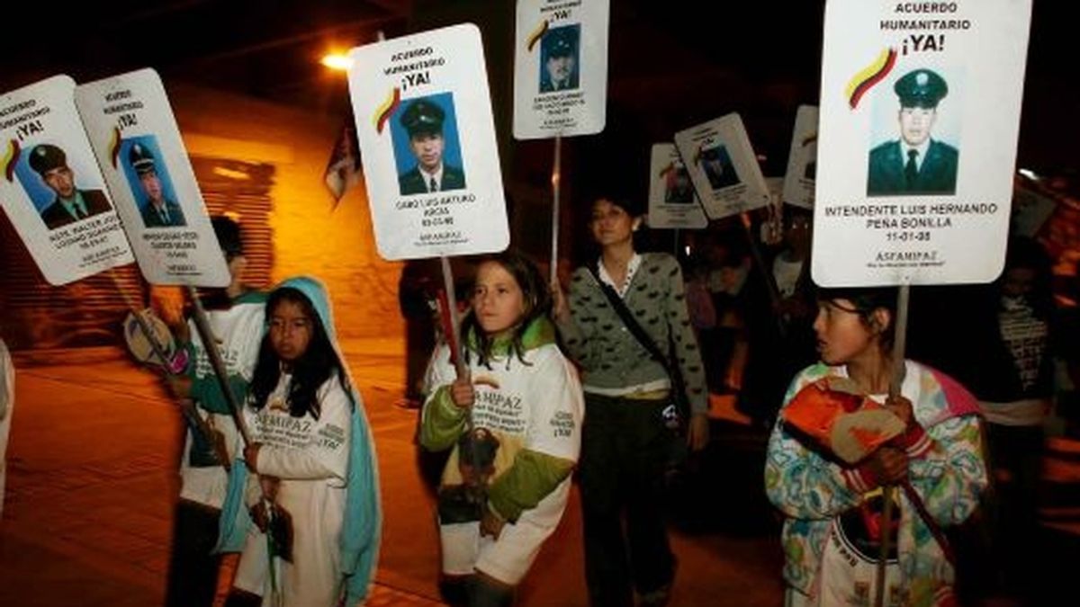 Un grupo de niños camina con carteles con las fotos de sus familiares secuestrados por las FARC por una céntrica vía de Bogotá, después de que la guerrilla anunciara la decisión de liberar a seis rehenes. FOTO: EFE.