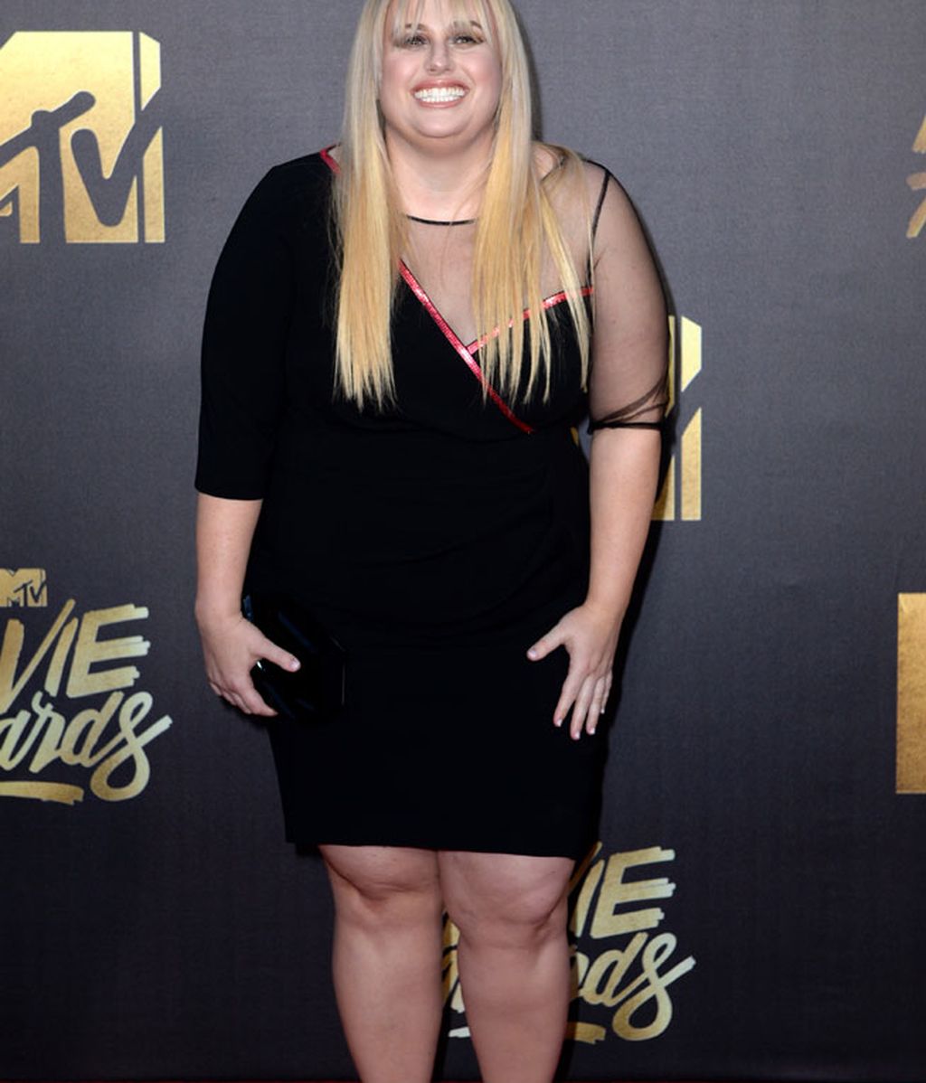 Rebel Wilson con vestido negro corto y mangas asimétricas