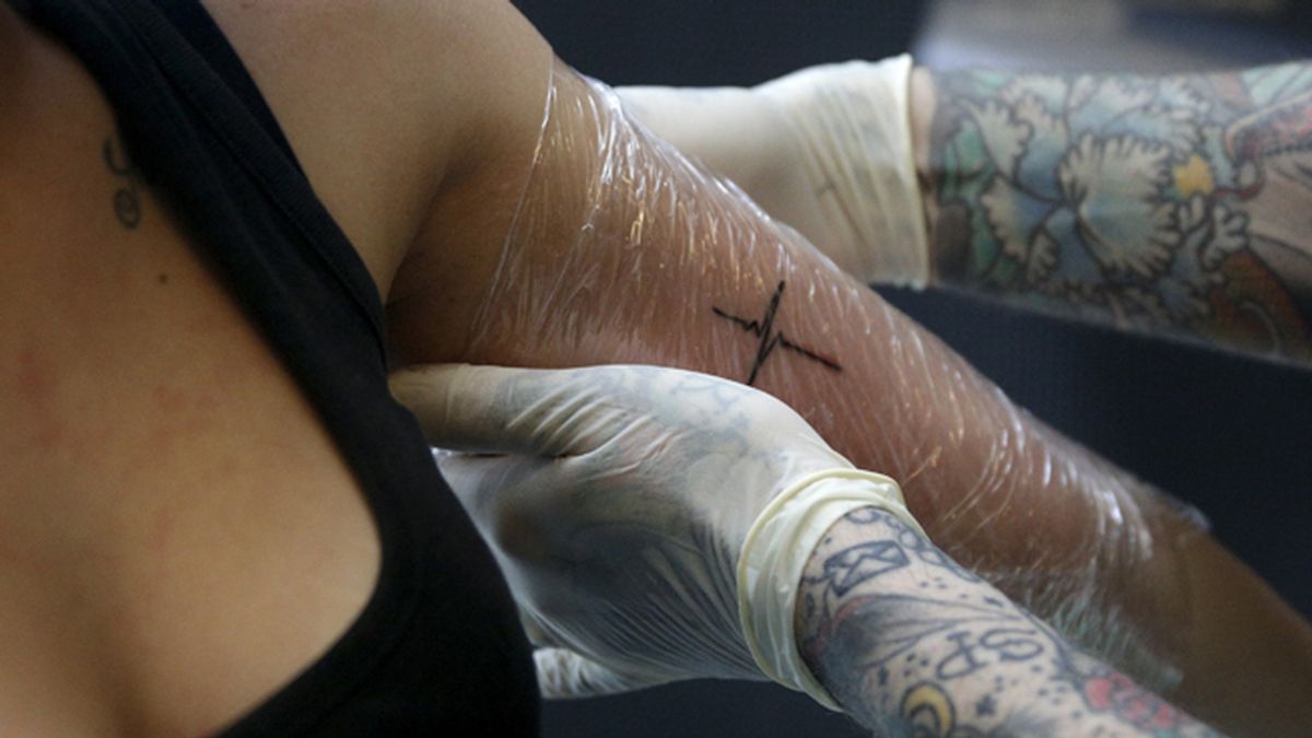 Un tatuador tatúa el brazo a una mujer