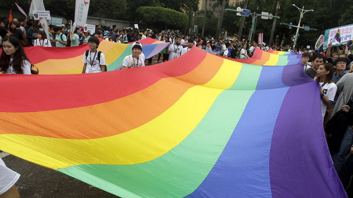 Manifestantes sujetan una bandera gay