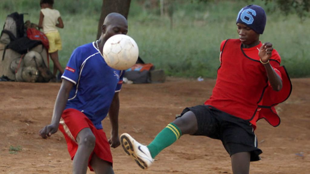 Dos jóvenes juegan al fútbol en la calle