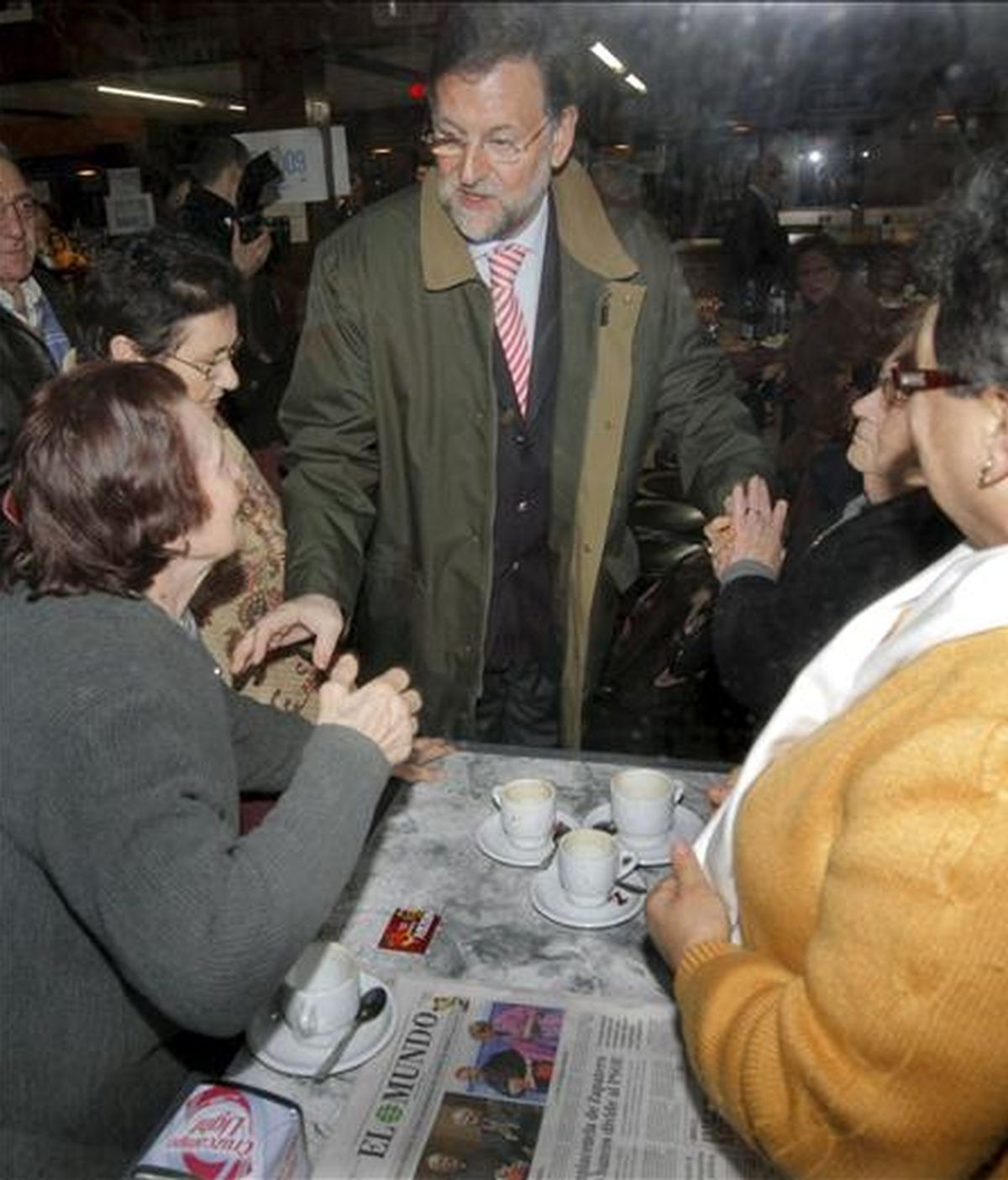 El presidente del PP, Mariano Rajoy, saluda a varias mujeres en una cafetería de la localidad coruñesa de Rianxo, antes de participar en varios actos preelectorales de su partido. EFE