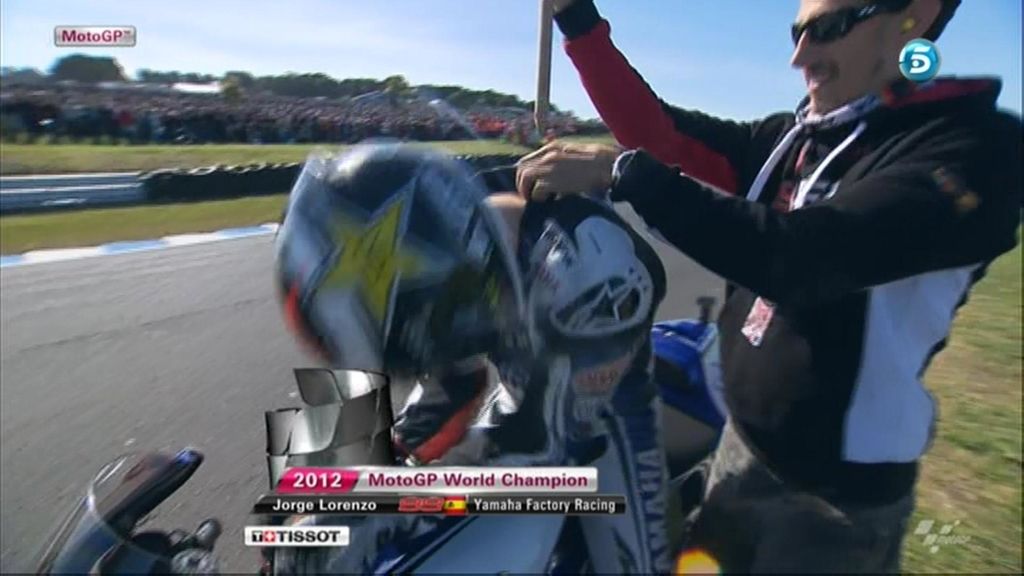 Un compañero coloca la bandera en la espalda de Jorge Lorenzo