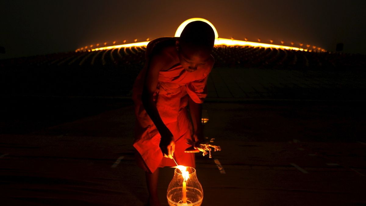 Monje budista enciende una vela en el Makha Bucha