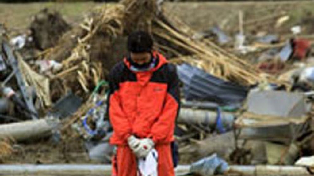 Un bombero guarda un minuto de silencio un mes después del seísmo que terremoto y posterior tsunami que arrasó la costa nororiental japonesa.
