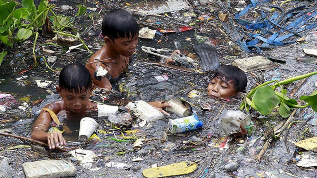 Niños filipinos nadando entre basura para sobrevivir