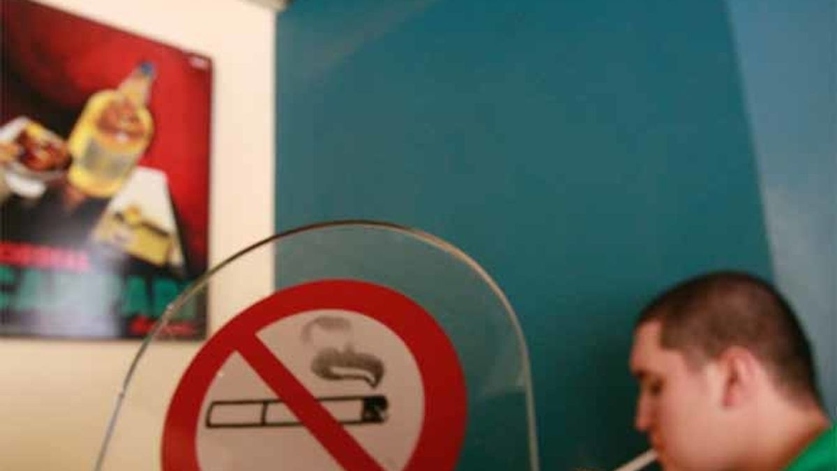 Un fumador se enciende un cigarro en un café de Atenas