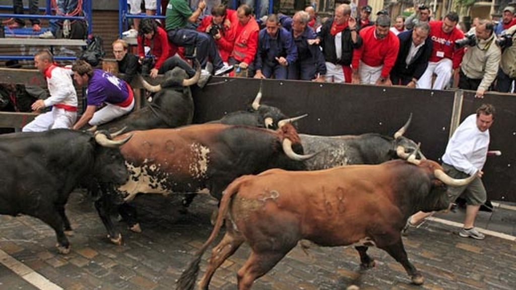 Varios mozos sortean a los toros en la curva de Mercaderes