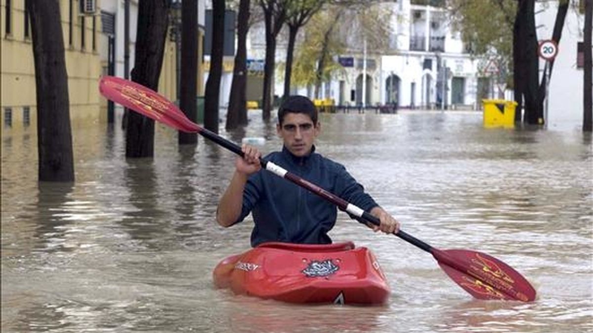 Un joven se desplaza con una piragua por las calles de Écija (Sevilla) donde un treinta por ciento del casco urbano , con unos 40.000 habitantes, se encuentra inundado debido a las intensas lluvias de las últimas horas, que han dejado 107 litros de agua por metro cuadrado en la sierra de Córdoba, donde surge el río Genil, que pasa por Écija, cuya cota supera los 7,30 metros de altura. EFE