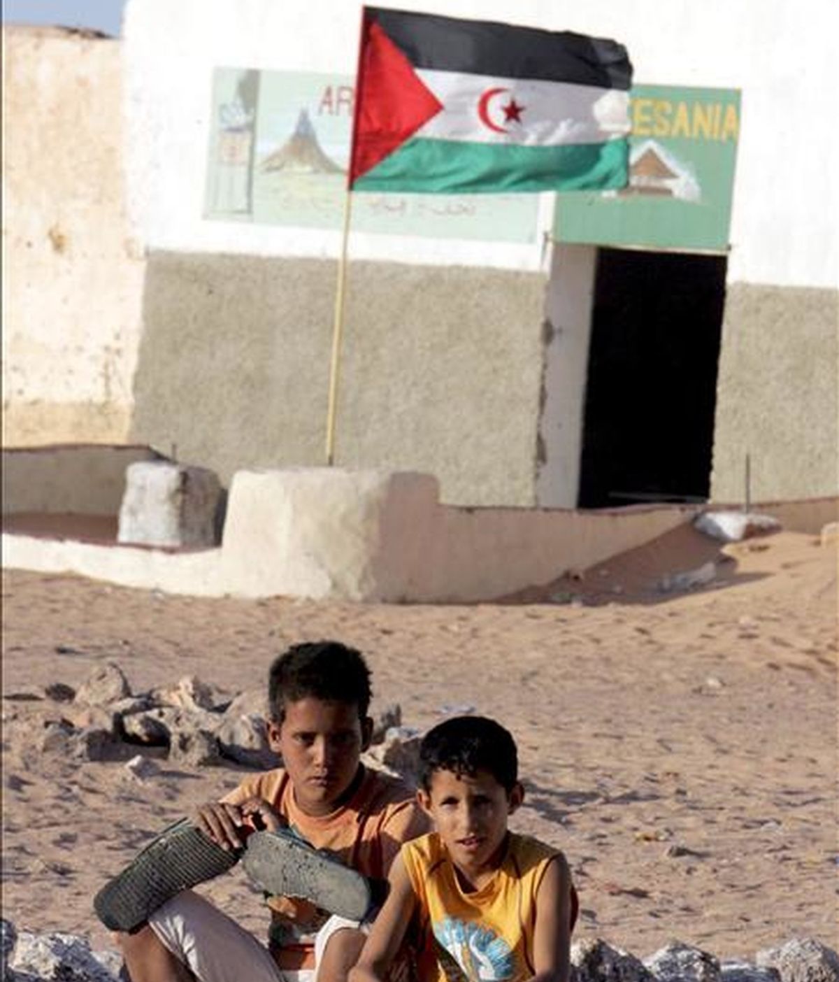Dos niños refugiados saharauis posan cerca de una bandera de la República Democrática Árabe del Sáhara al suroeste del desierto de Argelia. EFE/Archivo