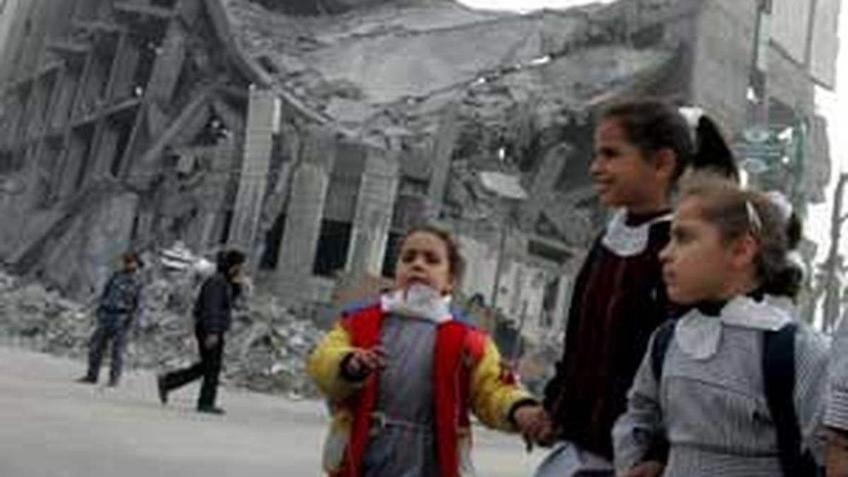 Niños palestinos pasan junto a un edificio en ruinas antes de su primer día de clase en una escuela de la Agencia de Naciones Unidas para los Refugiados Palestina en Oriente Próximo (UNRWA), en Gaza. Foto: EFE