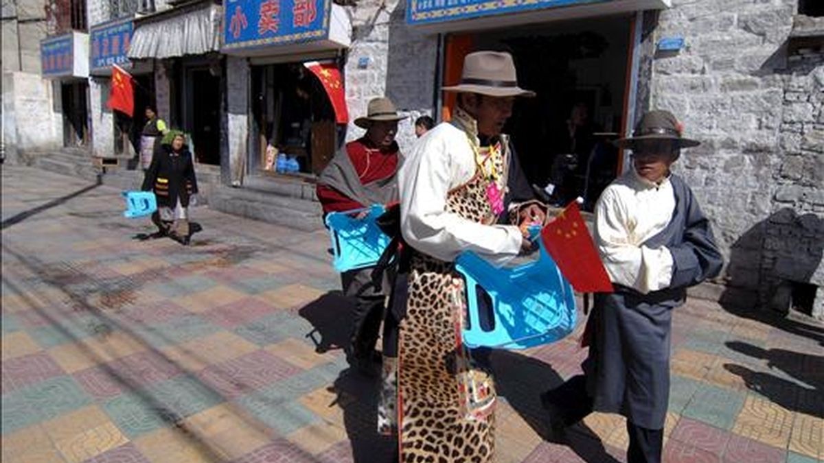 Tibetanos vestidos con trajes tradicionales sujetan banderas de China mientras se dirigen a las celebraciones del "Día de la Emancipación de los Siervos", una fiesta con la que Pekín quiere reivindicar su papel "liberador" en la región autónoma pero que el exilio tibetano califica de "celebración de 50 años de opresión", hoy en Lasha, China. EFE