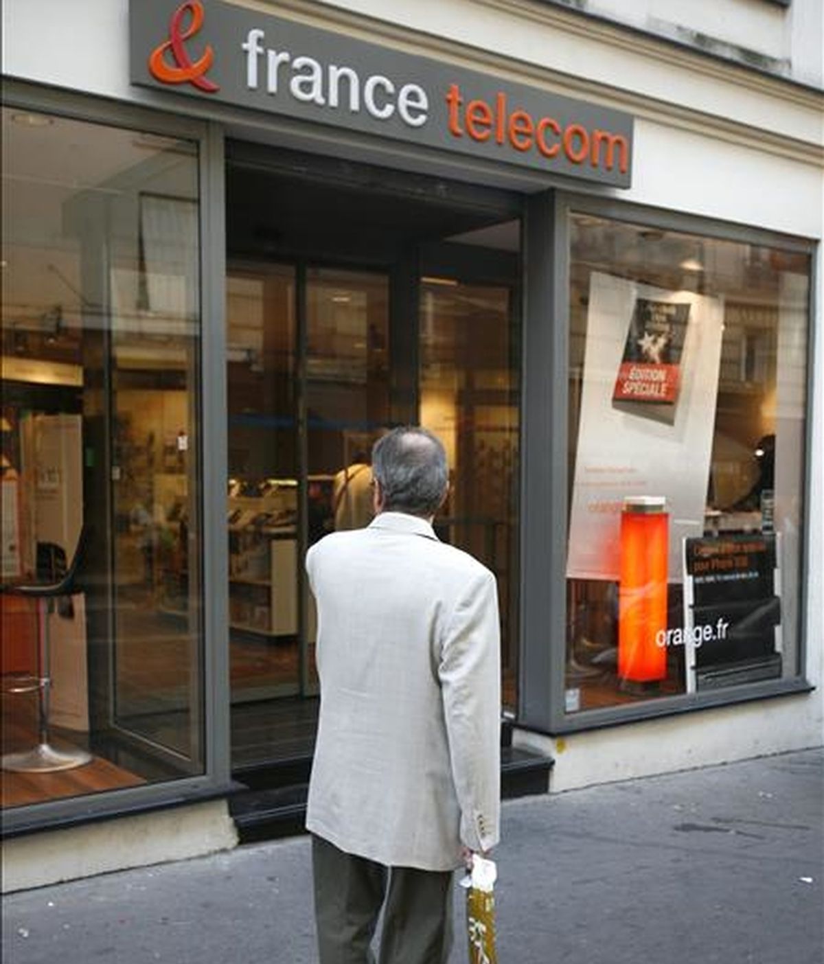 Un hombre camina por delante de una tienda de móviles France Telecom y Orange en París (Francia). EFE/Archivo
