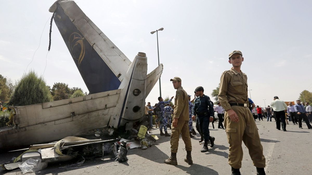 Agentes de policía y soldados iraníes inspeccionan la cola de un avión estrellado en Teherán, Irán,