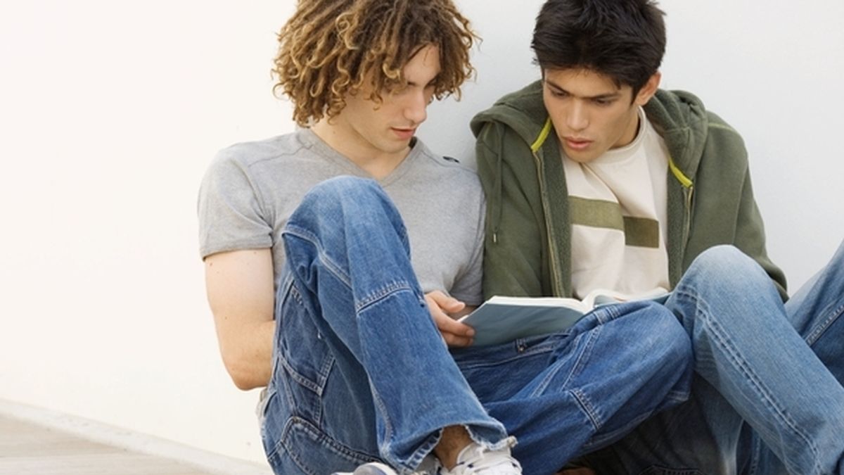 Dos jóvenes universitarios estudian juntos un manual