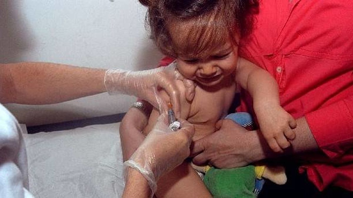 Una mujer pone una vacuna a una pequeña