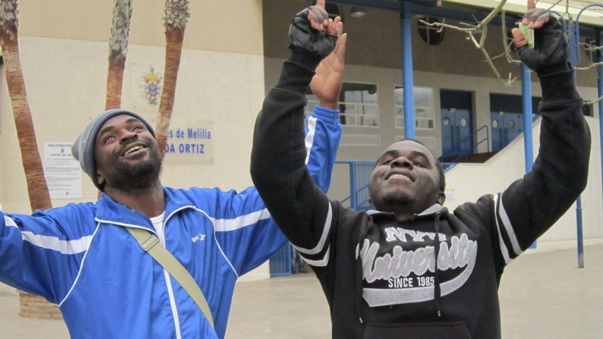 Dos inmigrantes celebran haber pasado la frontera de Melilla Dos inmigrantes celebran haber pasado la frontera de Melilla