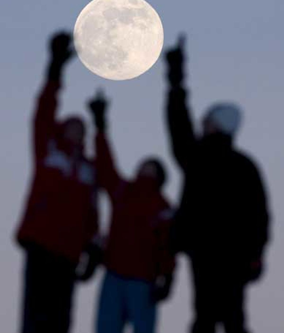 Jóvenes se fotografían con la luna llena. Foto: EFE