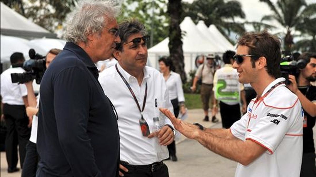 El piloto de Fórmula Uno Jarno Trulli (d), de Toyota, habla con el director de la escudería Renault, Flavio Briatore (i), y con un hombre no identificado, hoy en el circuito de Sepang (Malasia). EFE