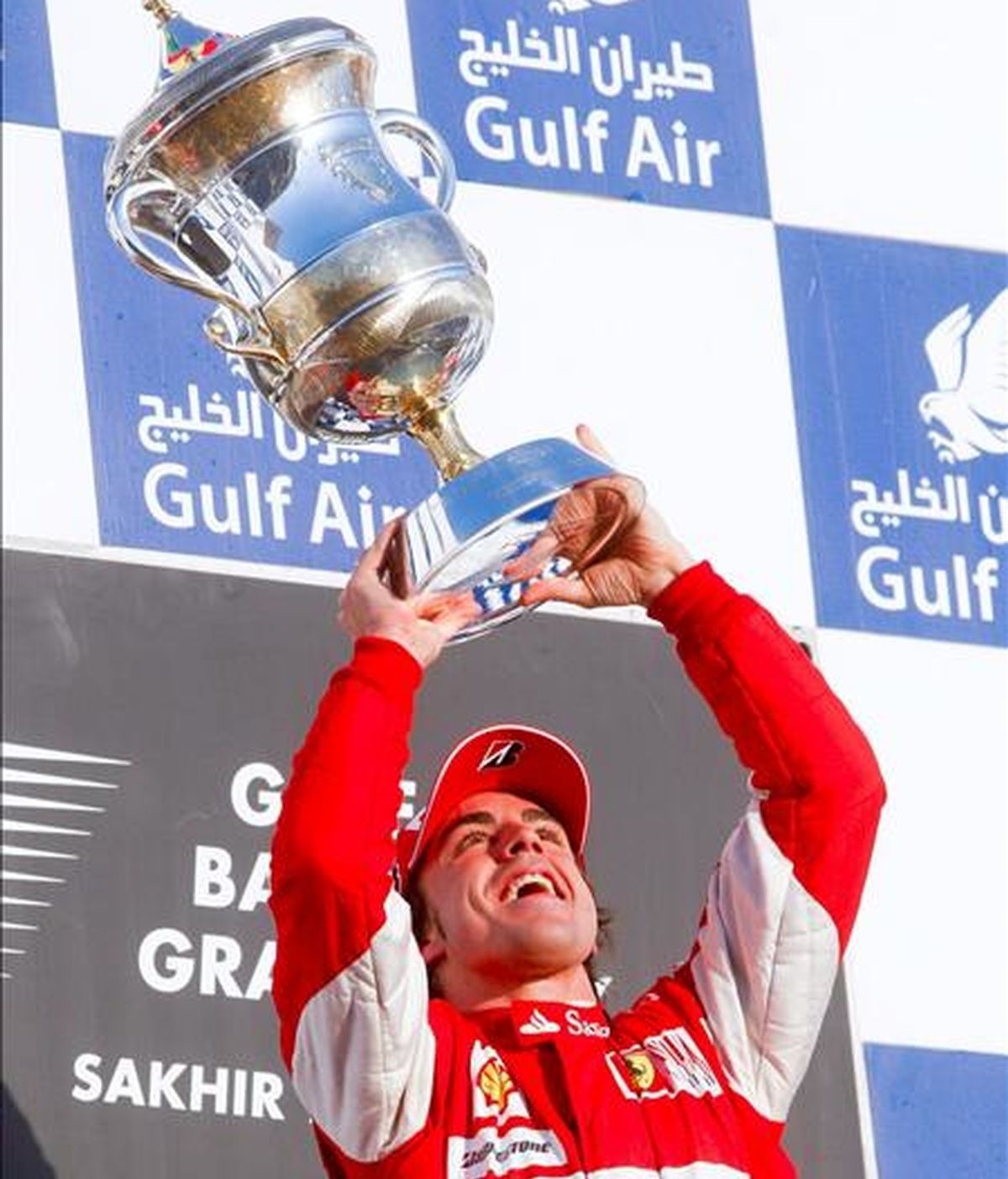 El piloto español de la escudería Ferrari, Fernando Alonso, levanta su trofeo de ganador en el podio del Gran Premio de Bahrein hoy en el Circuito Internacional de Bahrein en Sakhir. EFE