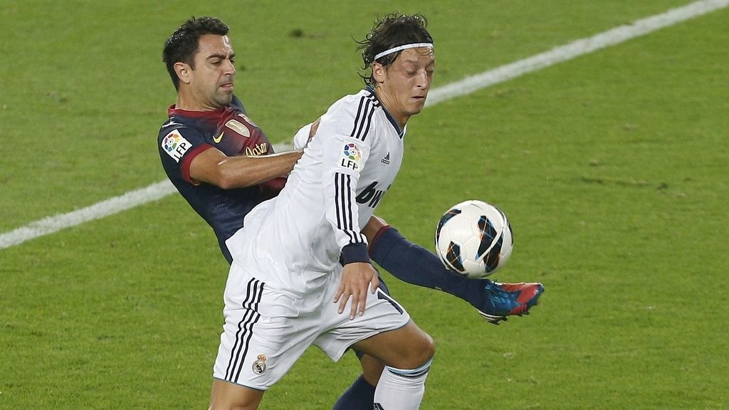 Özil y Xavi pelean por un balón