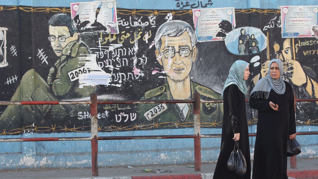 Mujeres palestinas pasean por un muro en el que aperecen pintados soldados israelíes en el norte de Gaza