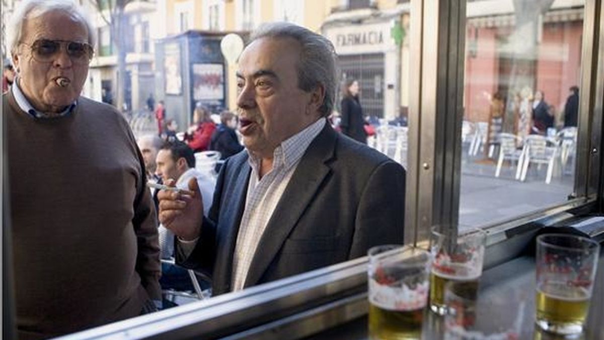 Varios hombres fuman en la puerta de un bar en la plaza de la Alfalfa de Sevilla, en el primer día de entrada en vigor de la nueva Ley Antitabaco en España. EFE