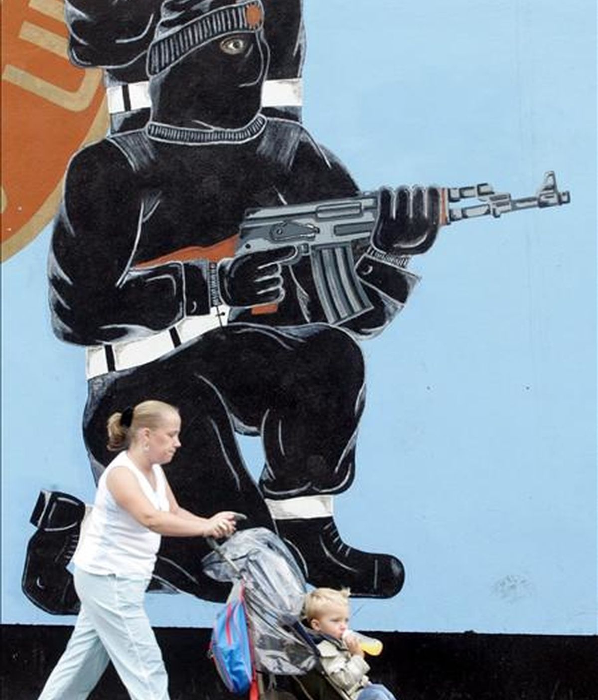 Una mujer pasea con su hijo por delante de un mural de la Fuerza de Voluntarios del Ulster (UVF) en la calle Shankill, oeste de Belfast. EFE/Archivo