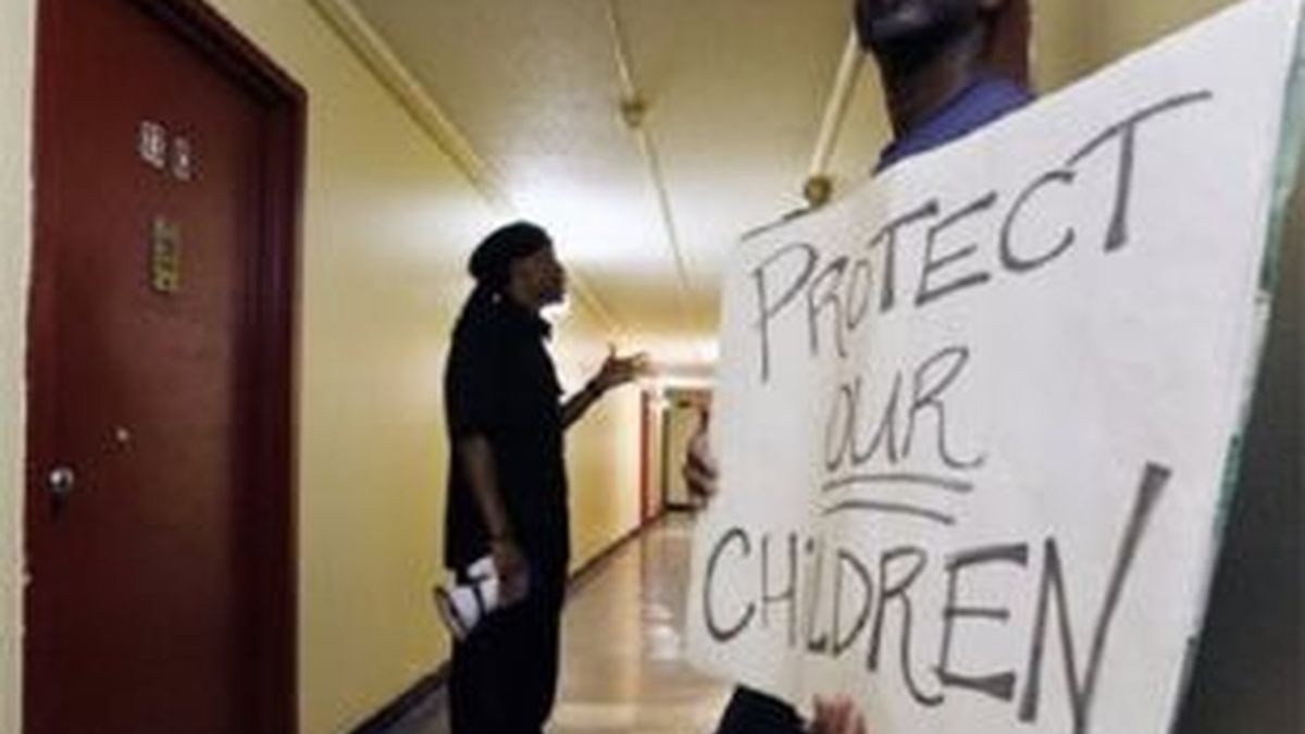 Un hombre exhibe un cartel de protesta ante la puerta del apartamento donde se produjo la violación de una menor, en la ciudad de Trenton. Foto: AP