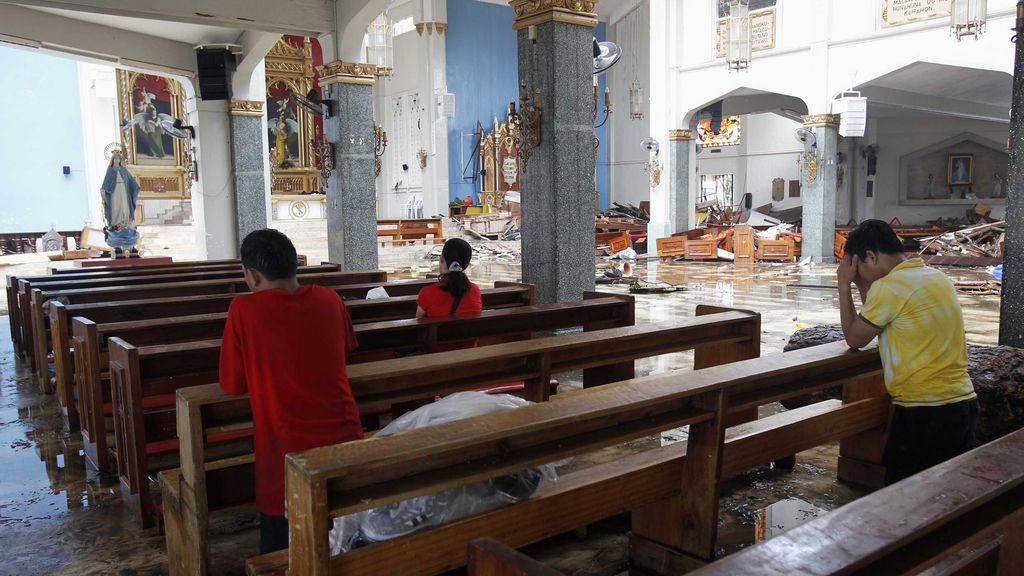 Tailandeses rezando en una Iglesia destrozada tras el paso del tifón