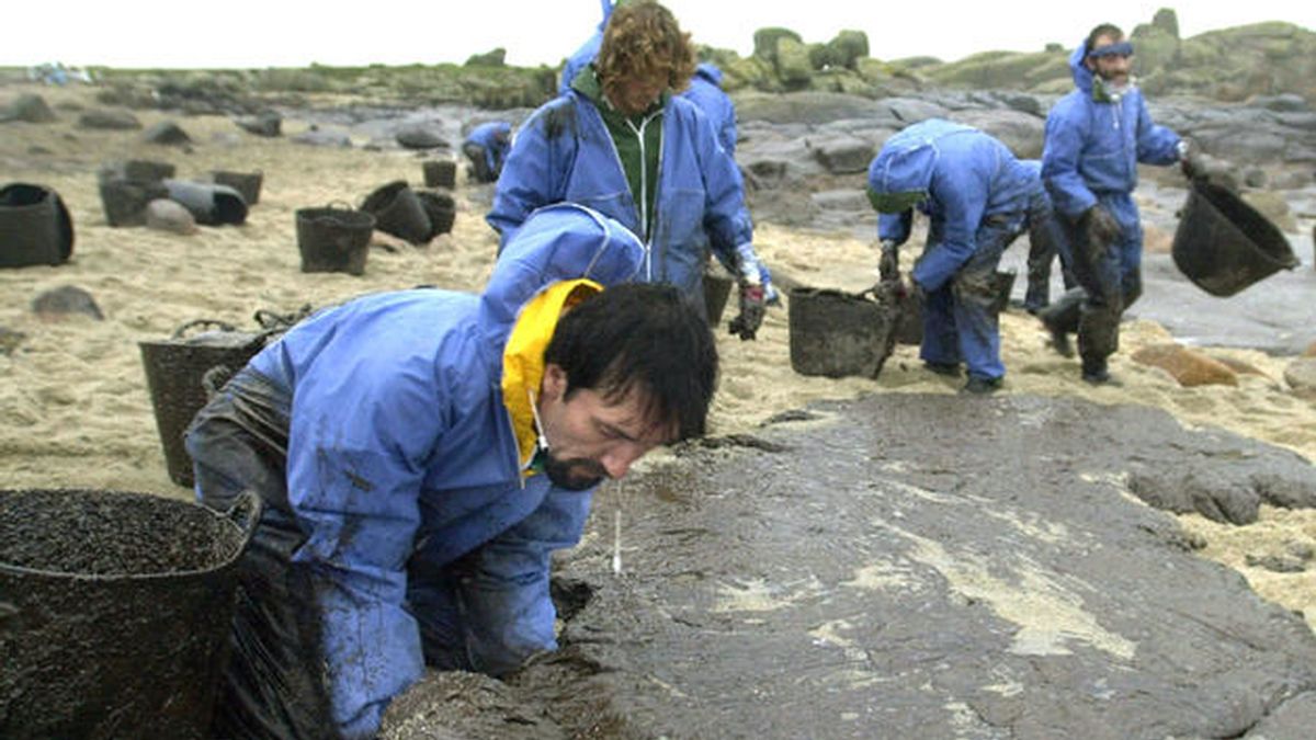 Un grupo de voluntarios limpia de fuel procedente del vertido del "Prestige" una cala de Carnota, a la hora de la comida de Navidad y bajo una fuerte lluvia en 2002 .