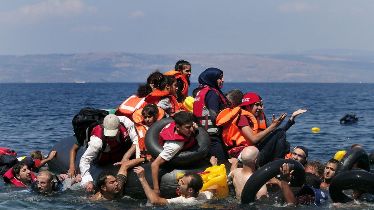 Refugiados sirios y afganos alrededor de un bote que desinfla antes de llegar a la isla griega de Lesbos