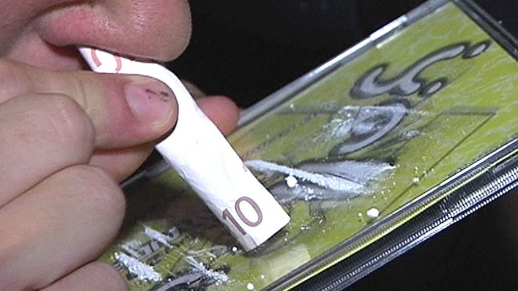 Un joven esnifa una raya de cocaína en un parking