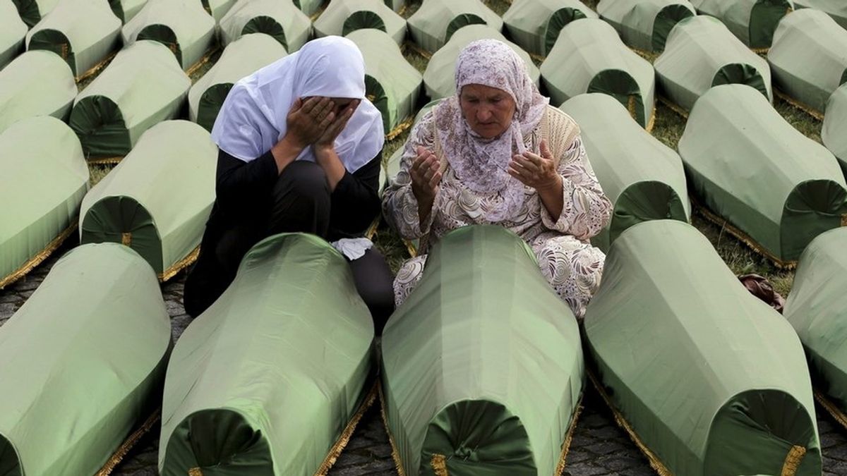 Mujeres rezan junto a féretros de sus familiares en Bosnia
