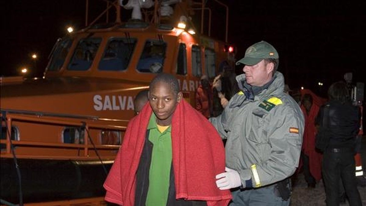 Uno de los 33 inmigrantes subsaharianos, rescatados ayer en la Isla de Alborán, que han llegado esta madrugada en buen estado, a bordo de la embarcación "Salvamar Hamal" de Salvamento marítimo, al Puerto de Motril (Granada) es ayudado por un guardia civil. EFE
