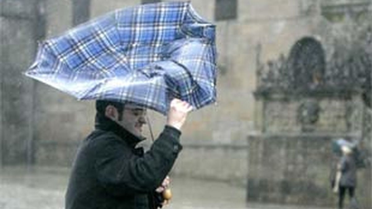 Una persona se resguarda de los fuertes vientos y la lluvia en Santiago de Compostela. Foto: EFE.