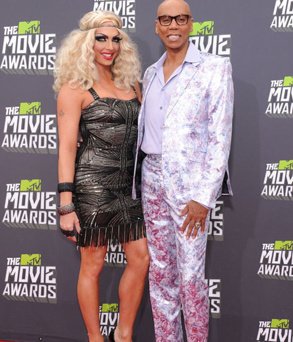 El actor y modelo RuPaul, vistoso traje y llamativa acompañante