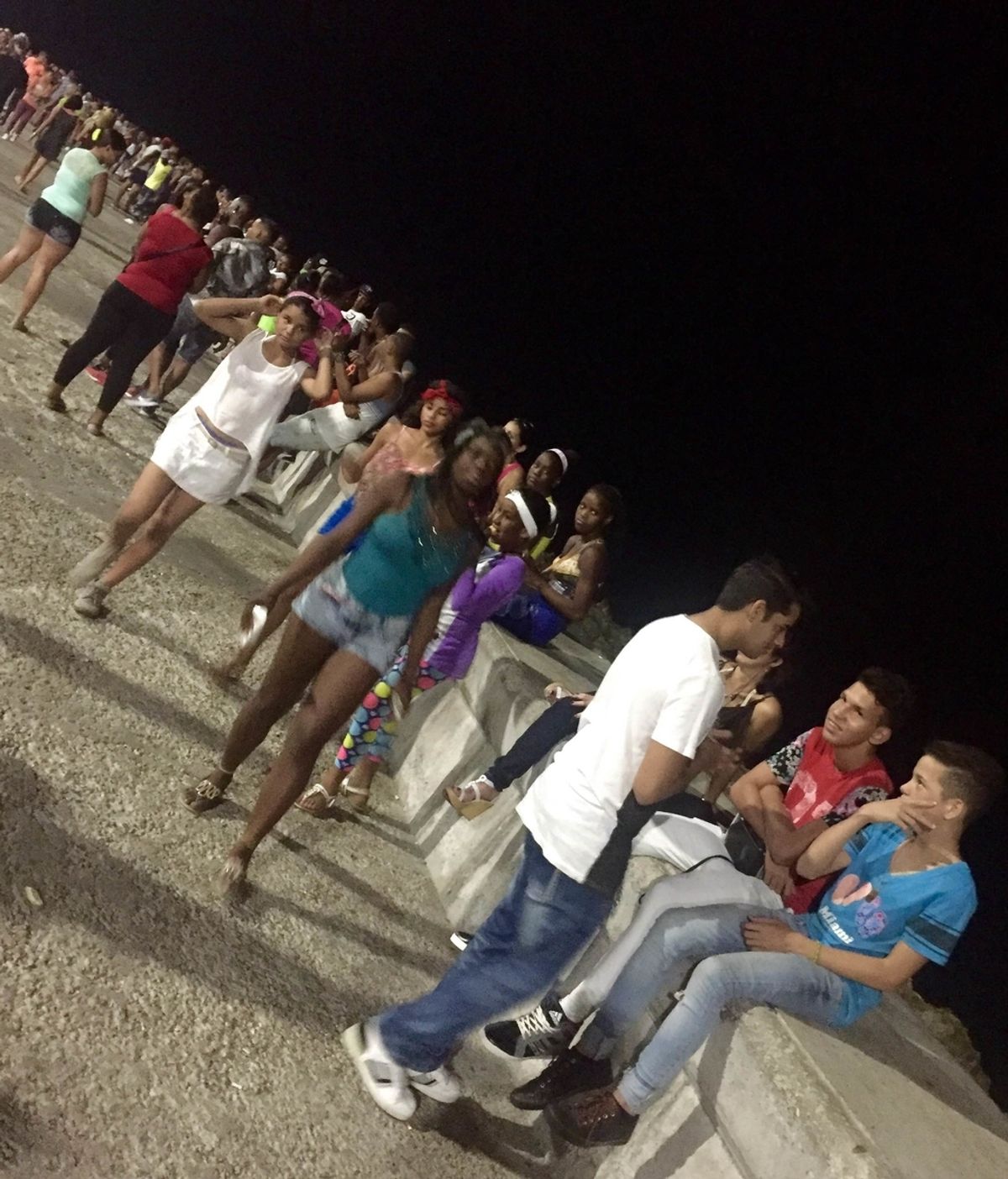 Cientos de jóvenes cubanos sentados a lo largo del Malecón