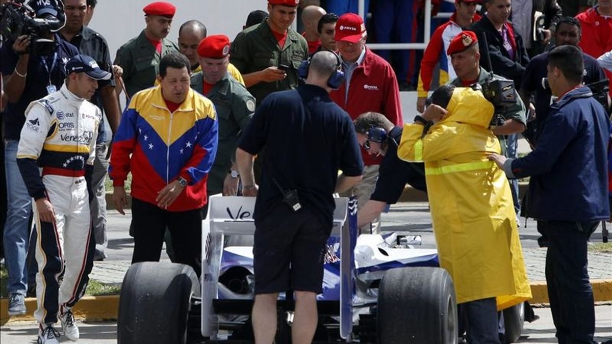 El piloto venezolano Pastor Maldonado (i), observa cómo el presidente venezolano, Hugo Chávez (2i), analiza su vehículo, antes de una exhibición al mando de un Williams en el Paseo de los Próceres de Caracas (Venezuela). EFE