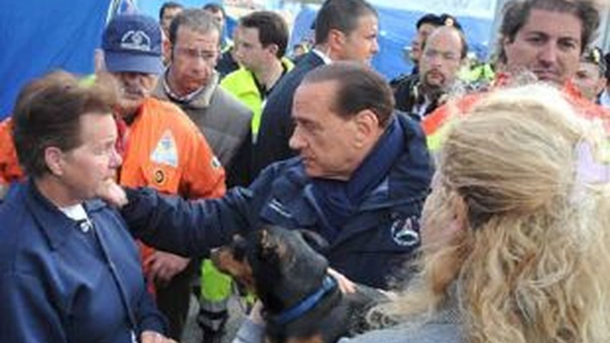 El primer ministro italiano, Silvio Berlusconi, (c), charla con una mujer víctima del terremoto, (i), en el campo de evacuados de Monticchi, cerca de L'Aquila. Foto: EFE