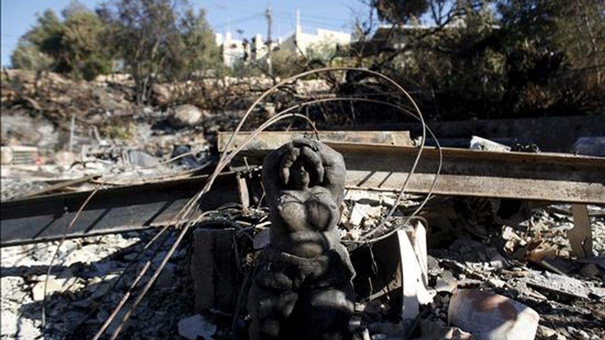La estatua de una mujer entre los restos de una vivienda en la aldea de Ein Hod, en las afueras de Haifa, tras el mayor incendio de la historia en Israel, que sigue activo en varias áreas del norte del país, hoy. EFE
