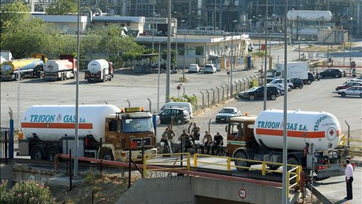 Camiones haciendo fila para llenar los tanques en una refineria a las afueras de Atenas, bajo la vigilancia de policías antidisturbios, este sábado. EFE