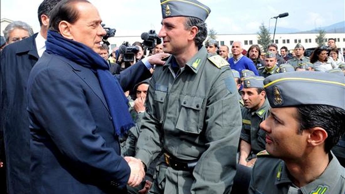El primer ministro italiano, Silvio Berlusconi (i),  saluda hoy a un oficial de aduanas en Coppito (Italia). Berlusconi llegó a la localidad, que está a 13 km de L'Aquila, para participar en la misa de Pascua de Resurrección. EFE