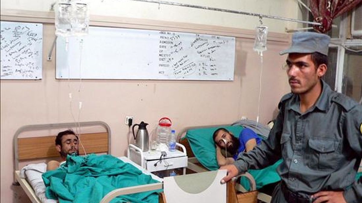 Un policía afgano vigila a dos heridos en un atentado suicida perpetrado en el distrito de Gerishk, situado en la provincia sureña de Helmand (Afganistán), en un hospital de Kandahar, hoy, 13 de junio. Ocho camioneros murieron y otras 21 personas sufrieron heridas en un ataque suicida contra un grupo de vehículos de suministro de las tropas de la OTAN en el sur de Afganistán, según informó una fuente oficial. EFE