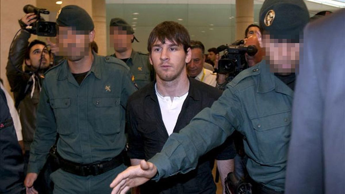 Leo Messi, escoltado por tres Guardias Civiles, a su llegada al aeropuerto de El Prat. FOTO: EFE.