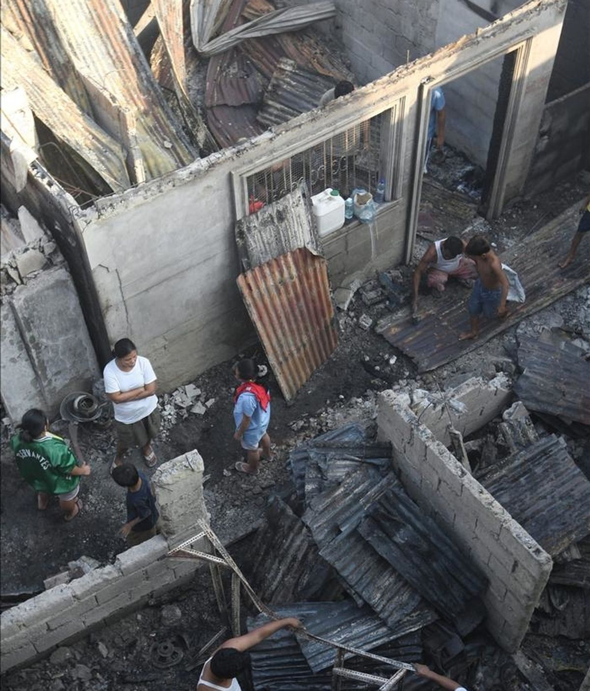 En la imagen, los filipinos regresan a sus humeantes hogares para ver qué se puede reutilizar este domingo, tras un incendio la noche anterior en Ciudad Navotas, al occidente de Manila, Filipinas.  EFE