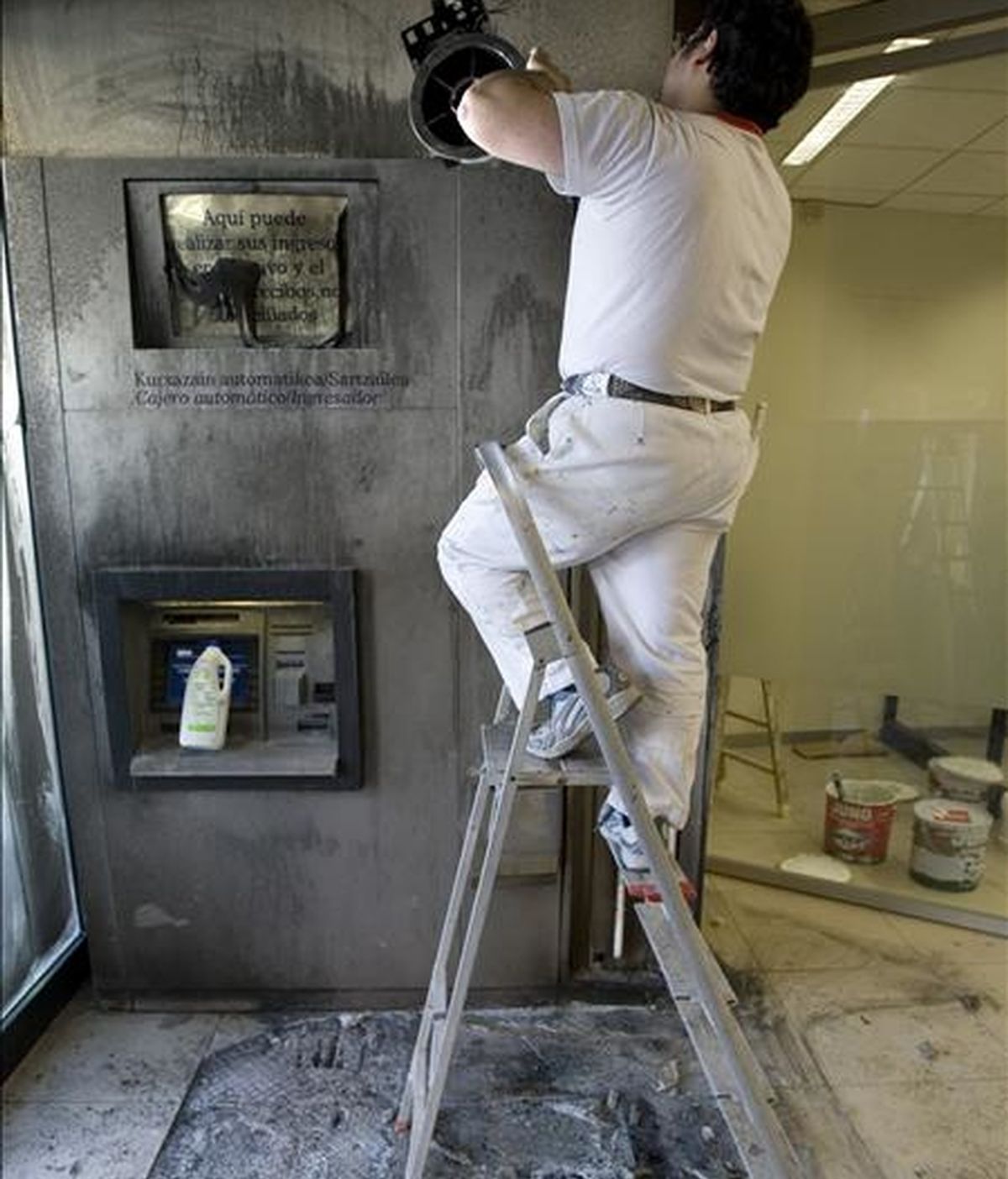 Un operario repara un cajero automático incendiado. EFE/Archivo