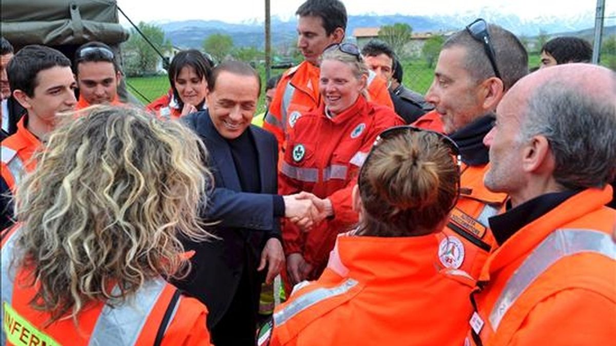 El primer ministro italiano Silvio Berlusconi conversa con efectivos del cuerpo de rescate durante su visita a las tiendas de campaña instaladas para los supervivientes del terremoto que sacudió Pianola, Italia, el 18 de abril de 2009. EFE