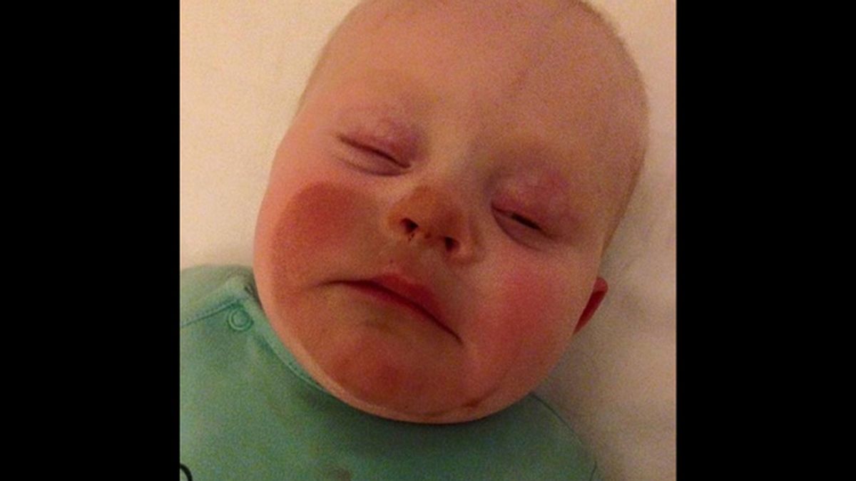 Una madre embadurna la cara de su bebé con spray autobronceador tras amamantarlo